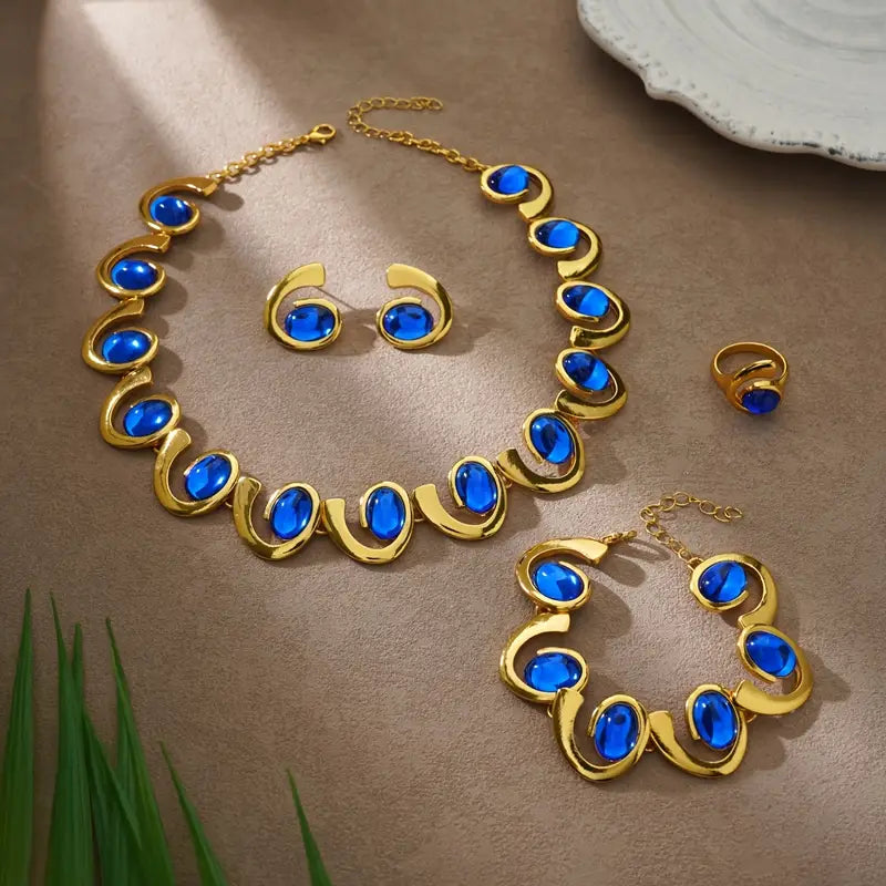 Um conjunto de quatro peças de joias femininas elegantes que destacam um bracelete, colar, anel e brincos em forma de espiral geométrica de acrílico azul, com tema de oceano. Este conjunto de joias metálicas é perfeito para férias na praia e festas.