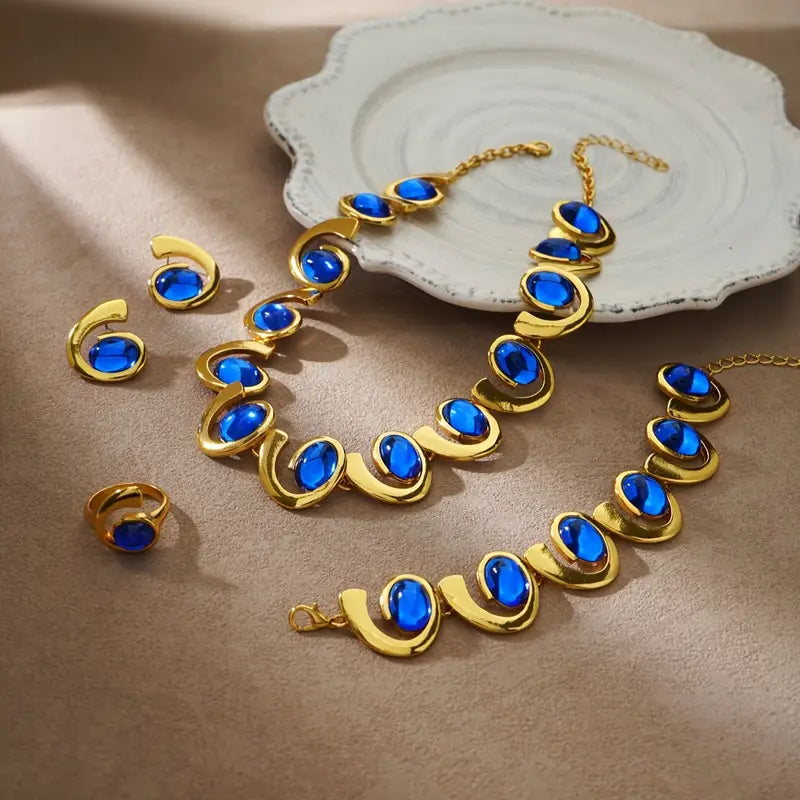 Um conjunto de quatro peças de joias femininas elegantes que destacam um bracelete, colar, anel e brincos em forma de espiral geométrica de acrílico azul, com tema de oceano. Este conjunto de joias metálicas é perfeito para férias na praia e festas.