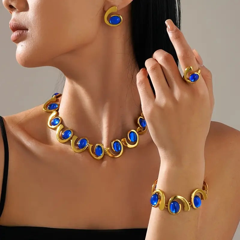 Um conjunto de quatro peças de joias femininas elegantes que destacam um bracelete, colar, anel e brincos em forma de espiral geométrica de acrílico azul, com tema de oceano. Este conjunto de joias metálicas é perfeito para férias na praia e festas.